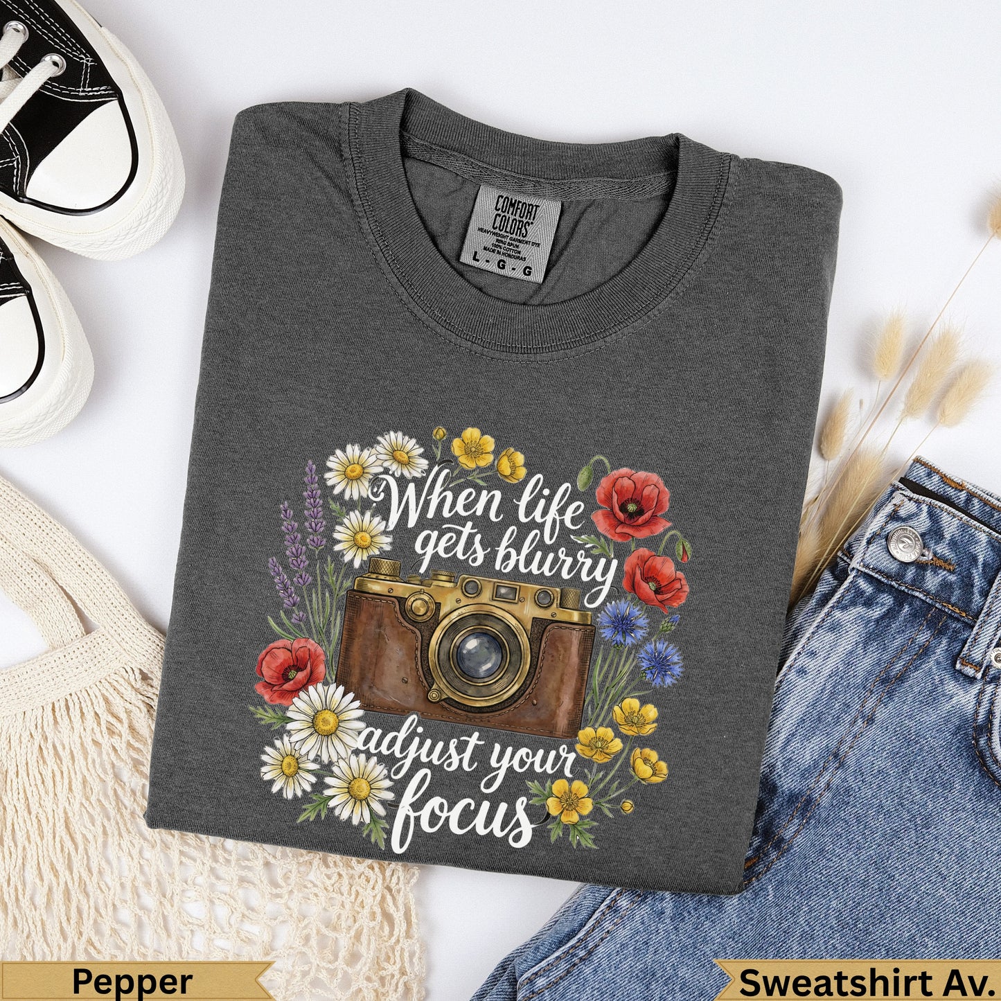 Dark gray t-shirt with a vintage camera and floral illustration, "When life gets blurry adjust your focus."