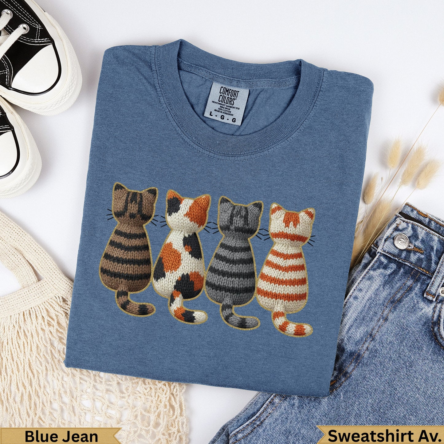 Blue t-shirt with four embroidered cats in a row.