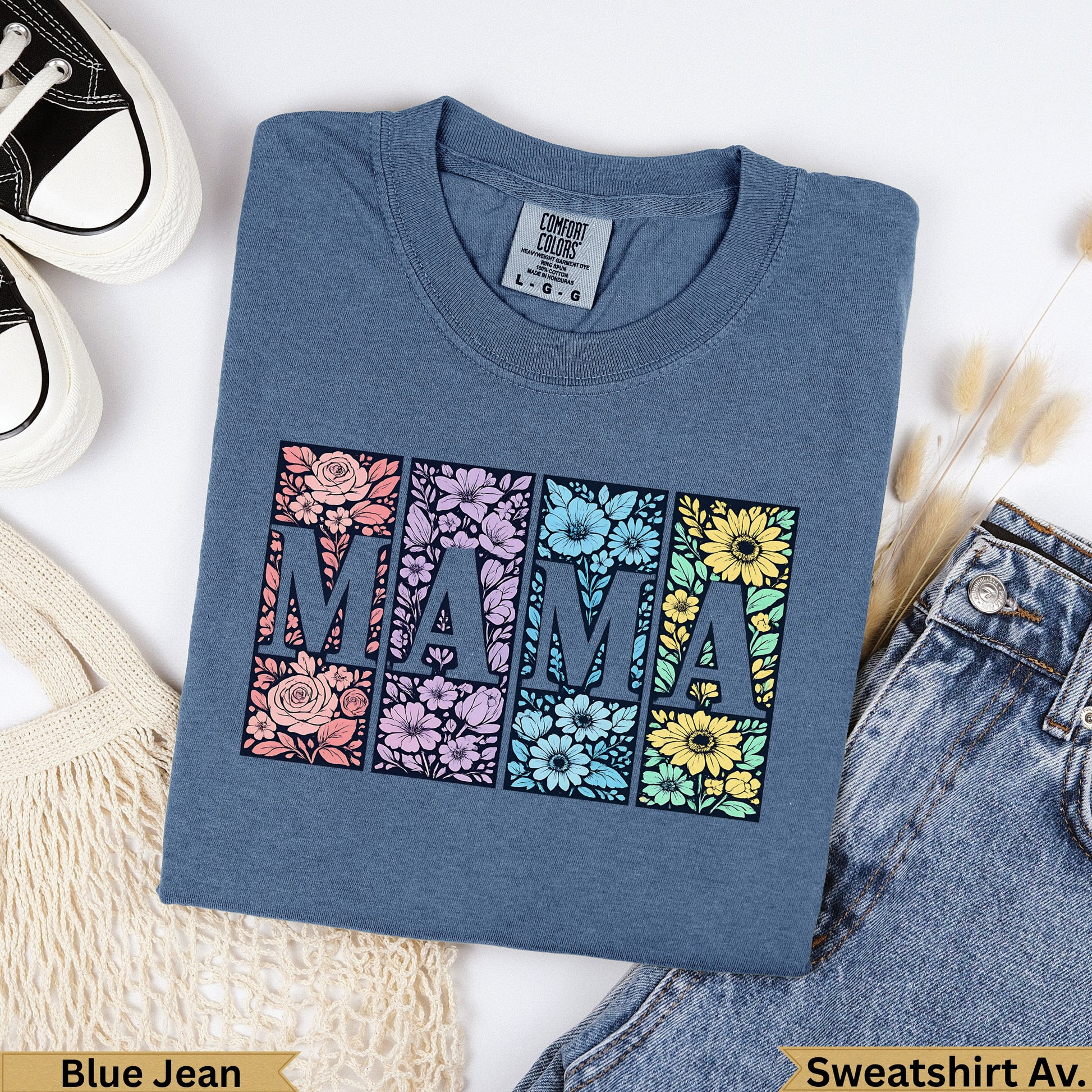 Blue t-shirt with "MAMA" in floral-filled squares, with jeans and a bag.