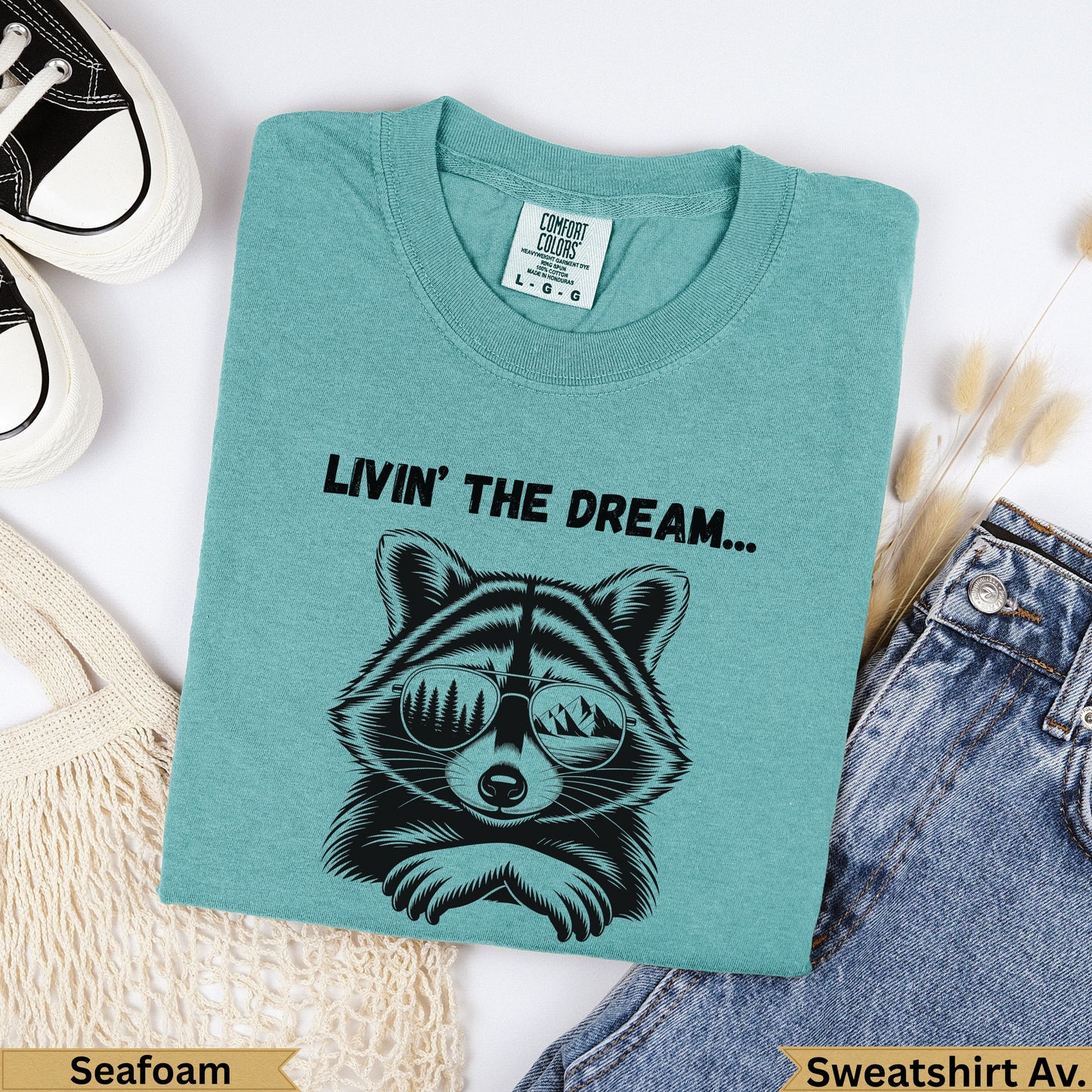 Teal Comfort Colors sweatshirt with raccoon graphic and text "LIVIN' THE DREAM...".