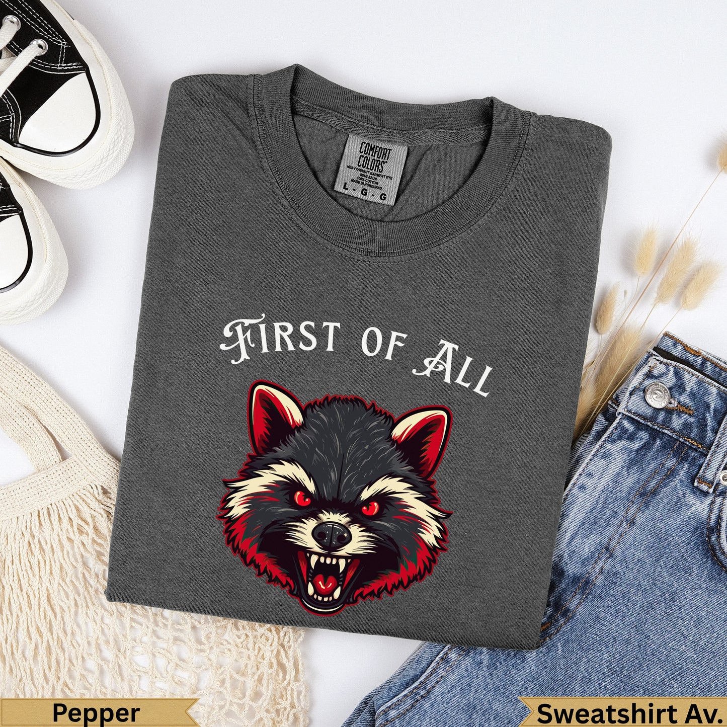 Dark gray t-shirt with "FIRST OF ALL" and a fierce raccoon graphic.