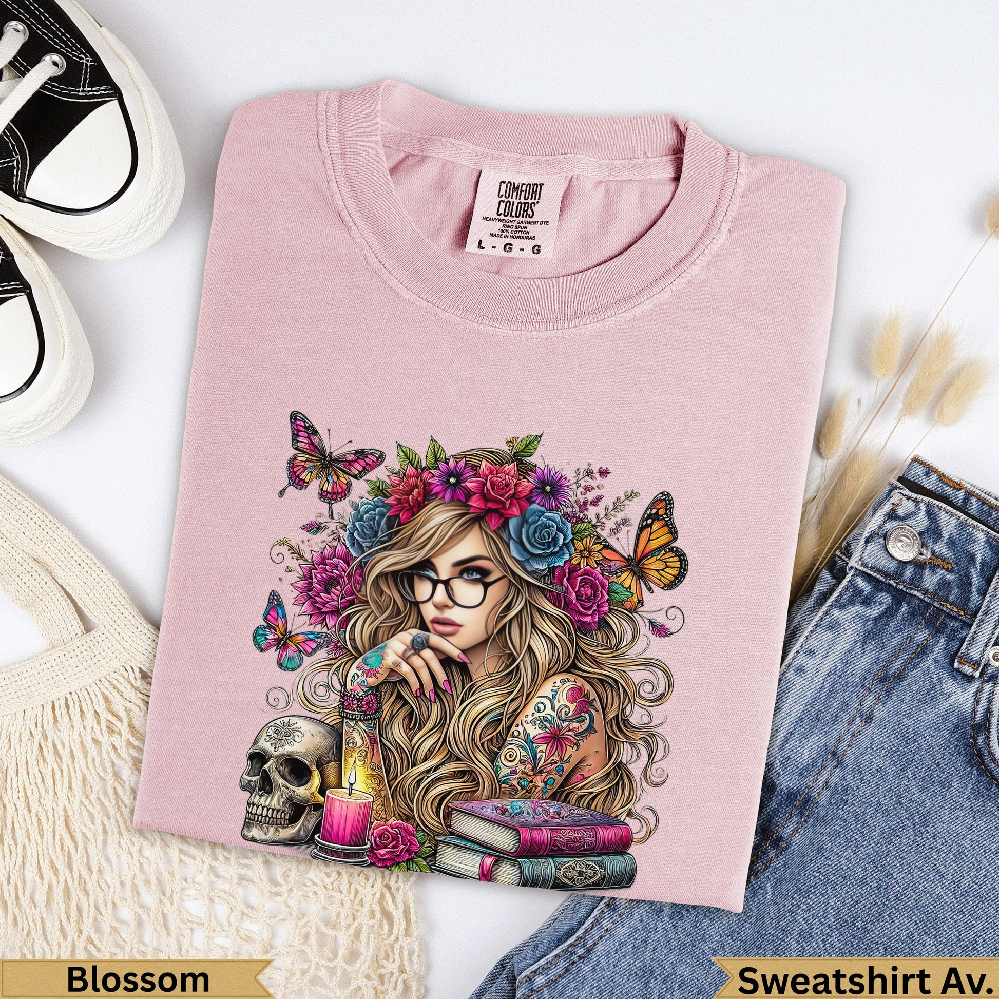 Pink sweatshirt with woman, flowers, butterflies, skull, and books illustration.