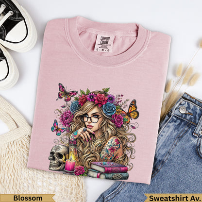 Pink sweatshirt with woman, flowers, butterflies, skull, and books illustration.