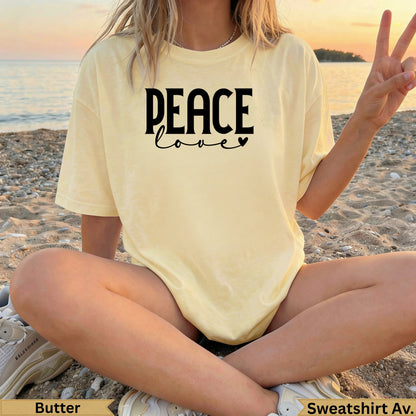 Yellow t-shirt with "peace love" graphic, worn by a person on a beach.