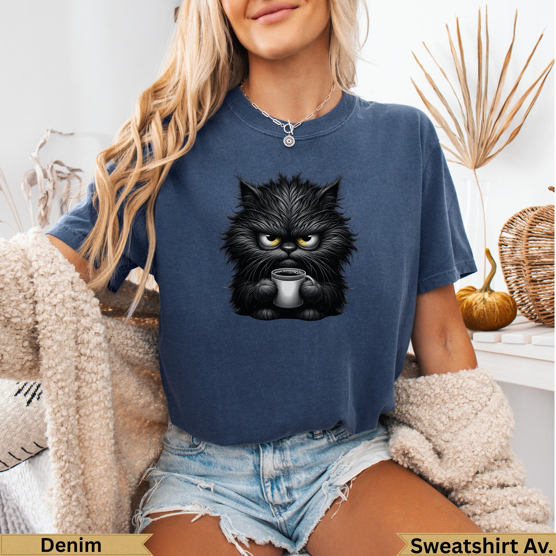 Grumpy black cat with coffee mug graphic on blue sweatshirt.