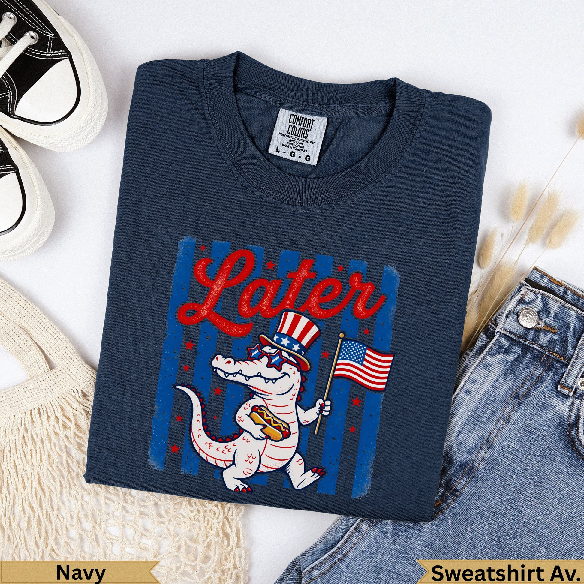 Navy t-shirt with alligator wearing sunglasses holding American flag and hot dog.