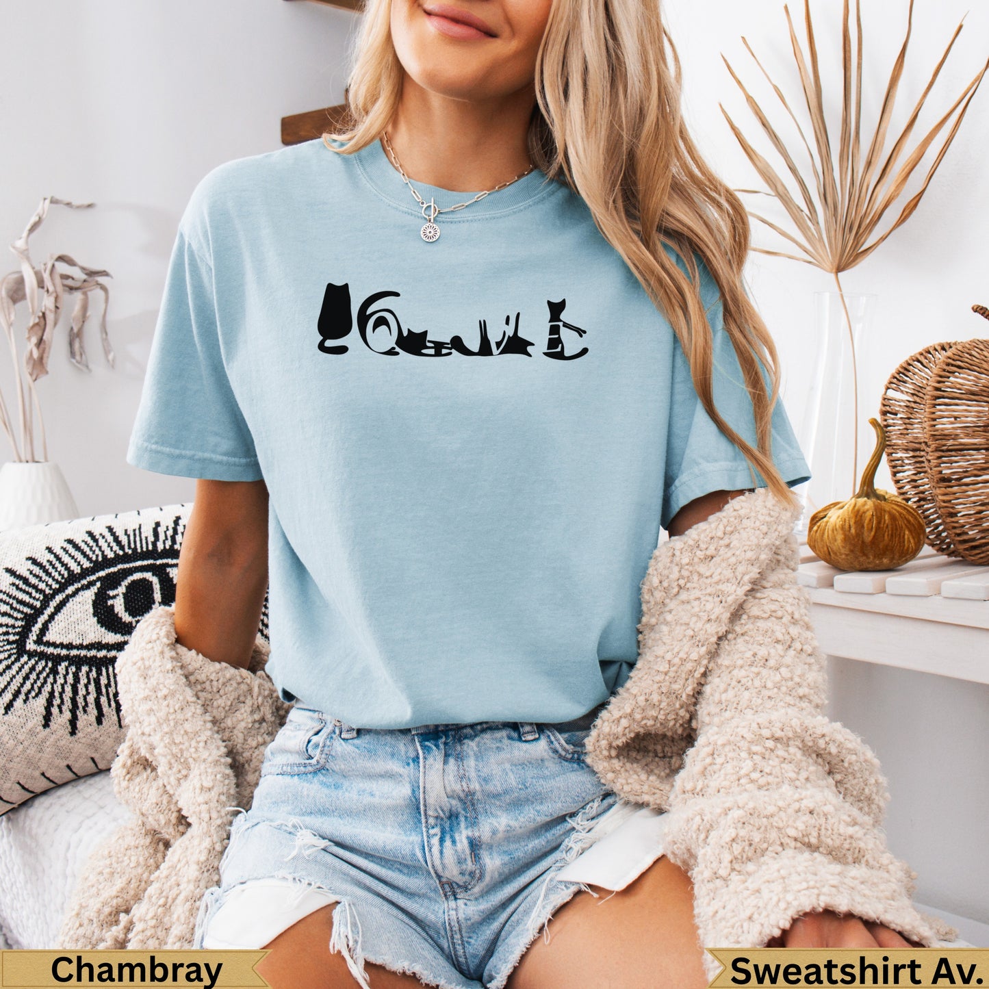 Light blue t-shirt with silhouette cats forming a word on the chest.