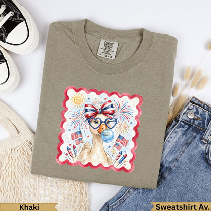Khaki t-shirt with a cartoon goose wearing glasses and celebrating Fourth of July.