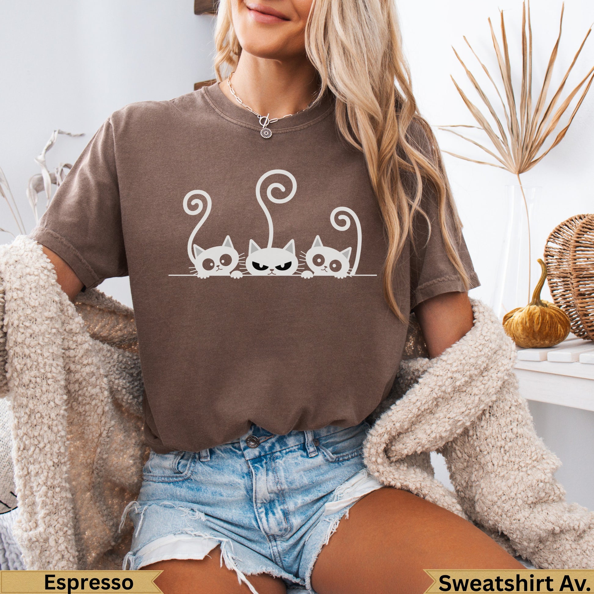 Three cartoon cats with grumpy expressions on a brown t-shirt.