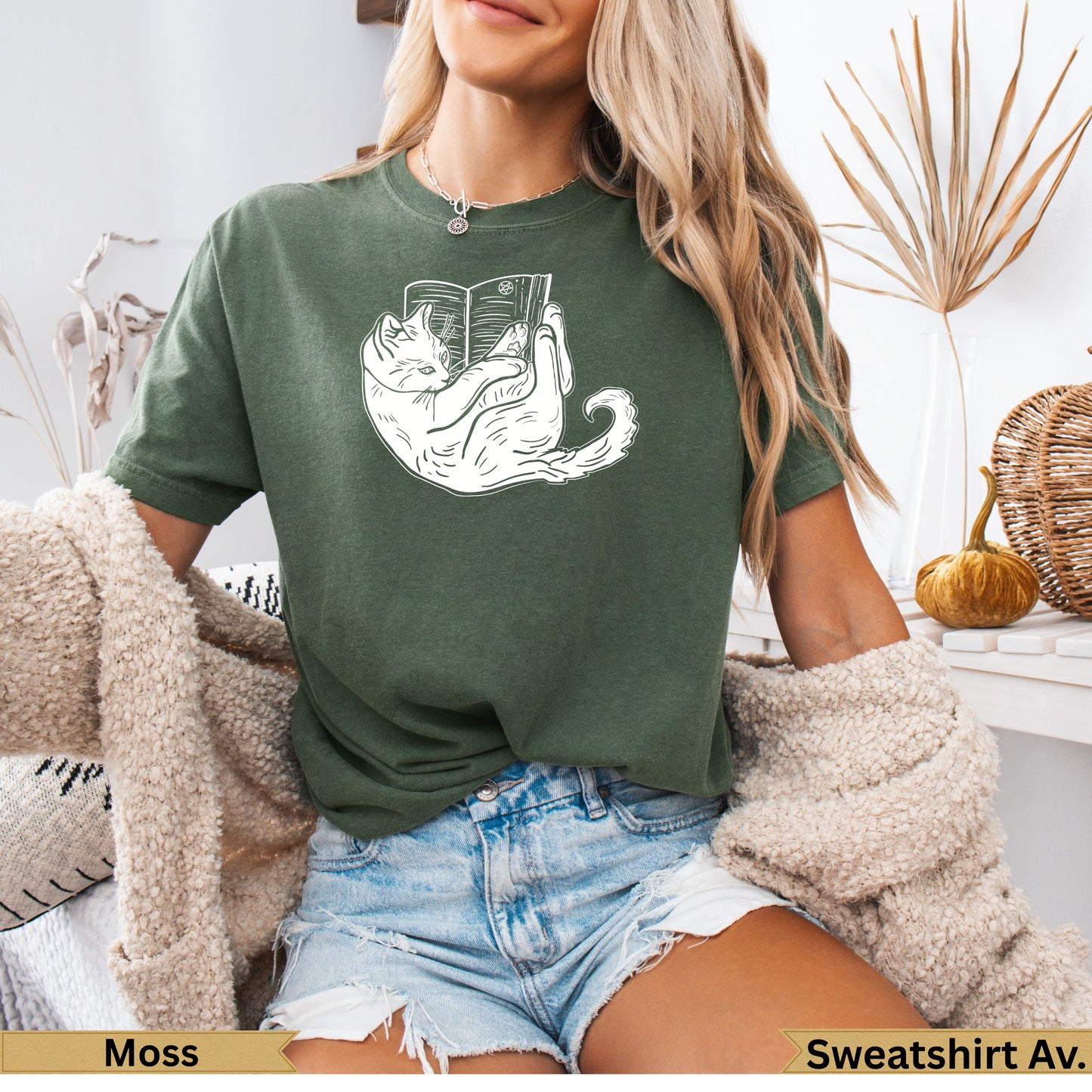 Green t-shirt with a white line drawing of a cat reading a book.